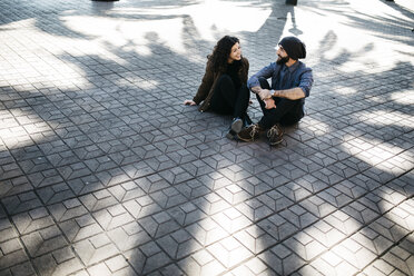Spain, Tarragona, Young couple talking, sitting in shadow - JRFF000466