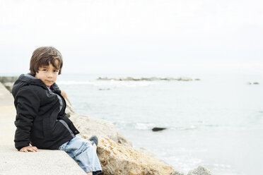 Porträt eines kleinen Jungen, der an einer Mauer vor dem Meer sitzt - VABF000231