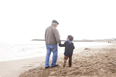 Großvater und Enkel gehen am Strand spazieren und unterhalten sich - VABF000246