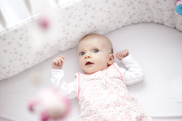 Weibliches Baby im Bett liegend, mit Blick auf ein Spielzeug - MFRF000502