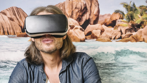 Portrait of man wearing Virtual Reality Glasses in front of photographic wallpaper stock photo