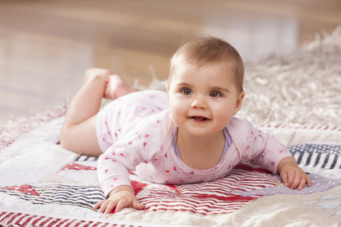 Porträt eines kleinen Mädchens, das auf einer Decke auf dem Boden liegt, lizenzfreies Stockfoto