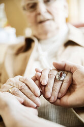 Adult daughter holding hands of her mother with Alzheimer's disease, close-up - JATF000846