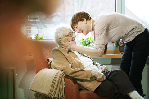 Adult daughter greeting her mother with Alzheimer's disease in her room at retirement home stock photo