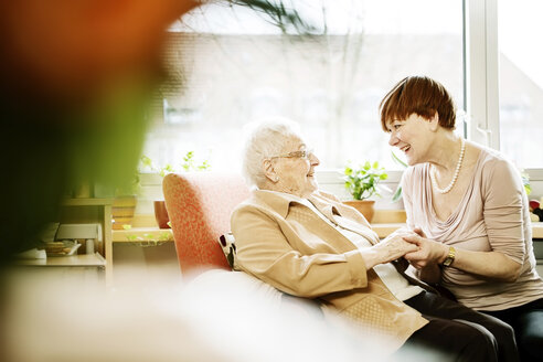 Erwachsene Tochter im Gespräch mit ihrer an Alzheimer erkrankten Mutter in ihrem Zimmer im Altersheim - JATF000850