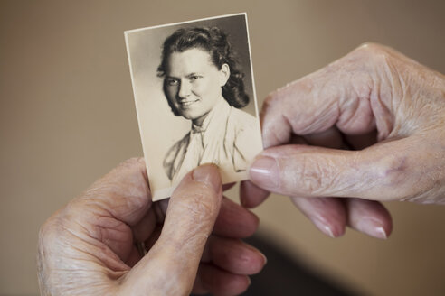 Die Hände einer älteren Frau, die eine alte Fotografie von sich selbst hält - JATF000852