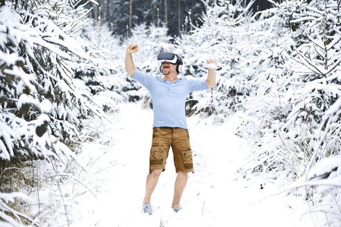 Glücklicher Mann mit Virtual-Reality-Brille in Winterlandschaft - MAEF011363