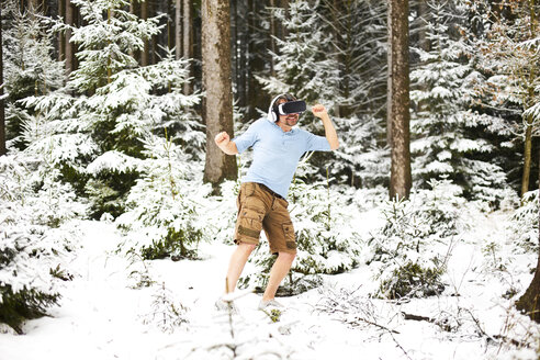 Glücklicher Mann mit Virtual-Reality-Brille in Winterlandschaft - MAEF011365