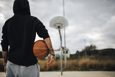 Mann spielt mit Basketball auf einem Platz im Freien - JRFF000480