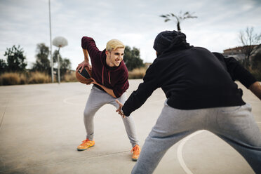 Zwei junge Männer spielen Basketball auf einem Platz im Freien - JRFF000482