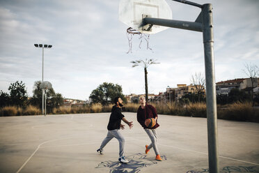 Two young men playing basketball on an outdoor court - JRFF000483