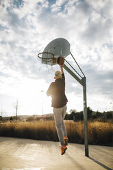 Junger Mann spielt Basketball auf einem Platz im Freien - JRFF000486