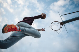 Junger Mann spielt Basketball auf einem Platz im Freien - JRFF000495