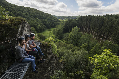 Deutschland, Westerwald, Hölderstein, drei Freunde auf dem Klettersteig machen eine Pause - PAF001553