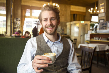Portrait of smiling young man in a cafe - SUF000061