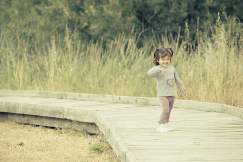 Spanien, lachendes kleines Mädchen auf der Holzpromenade stehend, lizenzfreies Stockfoto