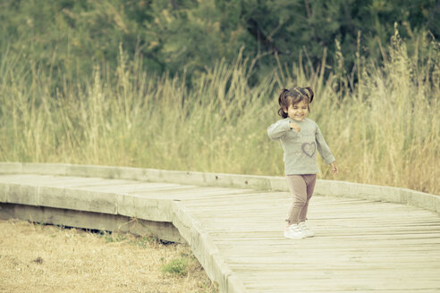 Spain, laughing little girl standing on wooden boardwalk - ERLF000148