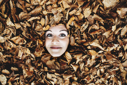 Woman's face in between autumn leaves - GEMF000766