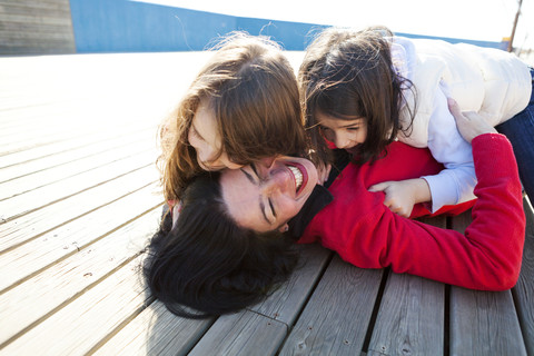 Mother and her two daughters playing on a deck stock photo