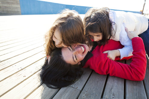 Mother and her two daughters playing on a deck - VABF000265