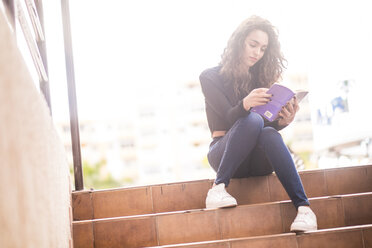 Teenager-Mädchen sitzt auf einer Treppe und liest ein Buch - SIPF000220