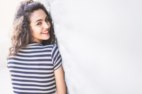 Porträt einer glücklichen Teenagerin, die über ihre Schulter schaut, lizenzfreies Stockfoto