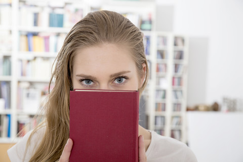 Porträt einer jungen Frau zu Hause mit einem Buch in der Hand, lizenzfreies Stockfoto