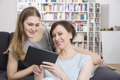 Mutter und erwachsene Tochter teilen sich ein digitales Tablet - FMKF002418