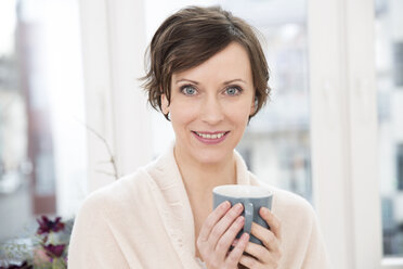 Portrait of smiling woman holding cup - FMKF002423