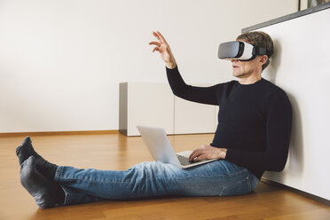 Man wearing virtual reality glasses using laptop - MFF002731