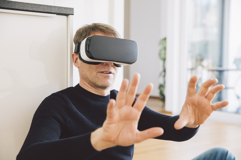 Mann trägt Virtual-Reality-Brille mit seinen Händen, lizenzfreies Stockfoto
