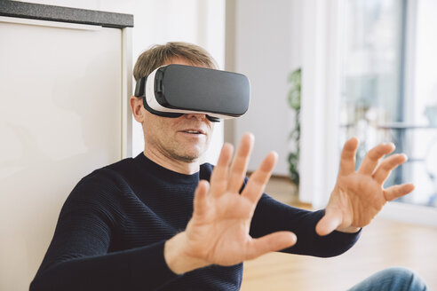 Mann trägt Virtual-Reality-Brille mit seinen Händen - MFF002732