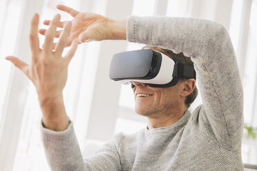 Mann trägt Virtual-Reality-Brille mit seinen Händen - MFF002738