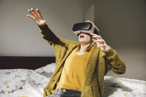Bewunderte Frau trägt Virtual-Reality-Brille mit ihren Händen, lizenzfreies Stockfoto