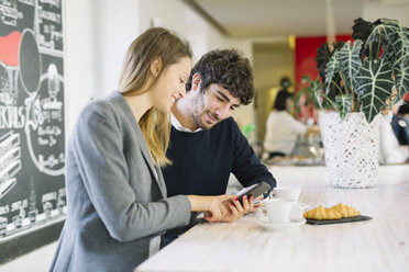 Zwei Kollegen in einem Café schauen auf ihr Handy - ALBF000026