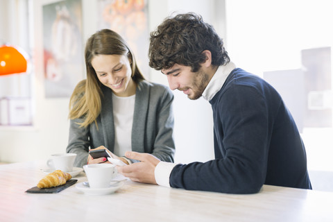 Zwei Kollegen in einem Café schauen auf ihre Handys, lizenzfreies Stockfoto