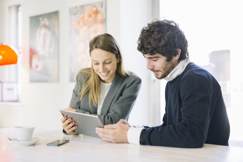 Zwei Kollegen in einem Café mit Blick auf ein digitales Tablet - ALBF000029