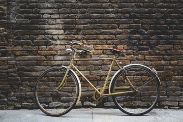 Vintage-Fahrrad lehnt an einer Backsteinmauer - GIOF000788