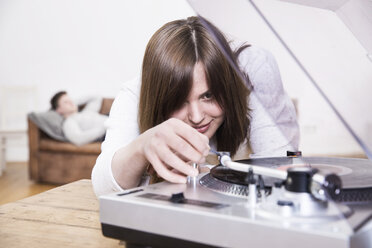 Young woman operating record player - FMKF002435