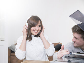 Glückliches junges Paar mit Plattenspieler und Kopfhörern - FMKF002436