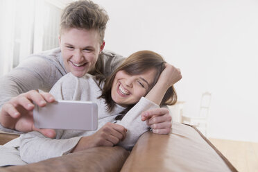 Playful young couple at home taking a selfie - FMKF002439