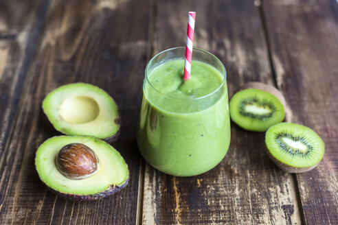 Glas Avocado-Kiwi-Smoothie und aufgeschnittene Früchte auf Holz - SARF002608