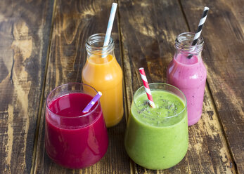 Glasses of four different smoothies on wood - SARF002609