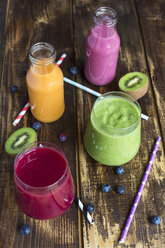 Glasses of four different smoothies and fruits on wood - SARF002610