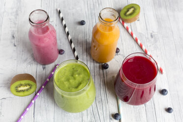 Glasses of four different smoothies and fruits on wood - SARF002611