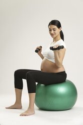 Schwangere Frau, die auf einem Fitnessball trainiert - SHKF000513