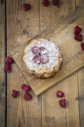 Stack of waffles with raspberries and icing sugar on wooden board - LVF004602