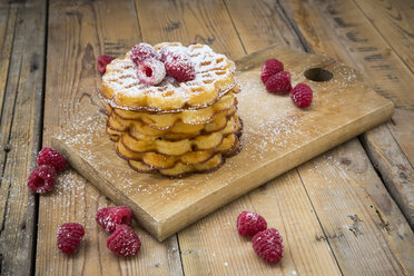Stack of waffles with raspberries and icing sugar on wooden board - LVF004603