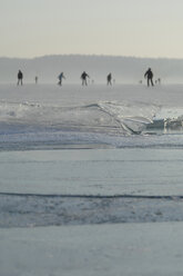 Deutschland, Menschen beim Schlittschuhlaufen auf einem zugefrorenen See mit dünner Eisdecke - CRF002744