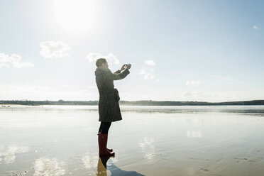 Frankreich, Bretagne, Finistere, Halbinsel Crozon, Frau beim Fotografieren am Strand - UUF006660